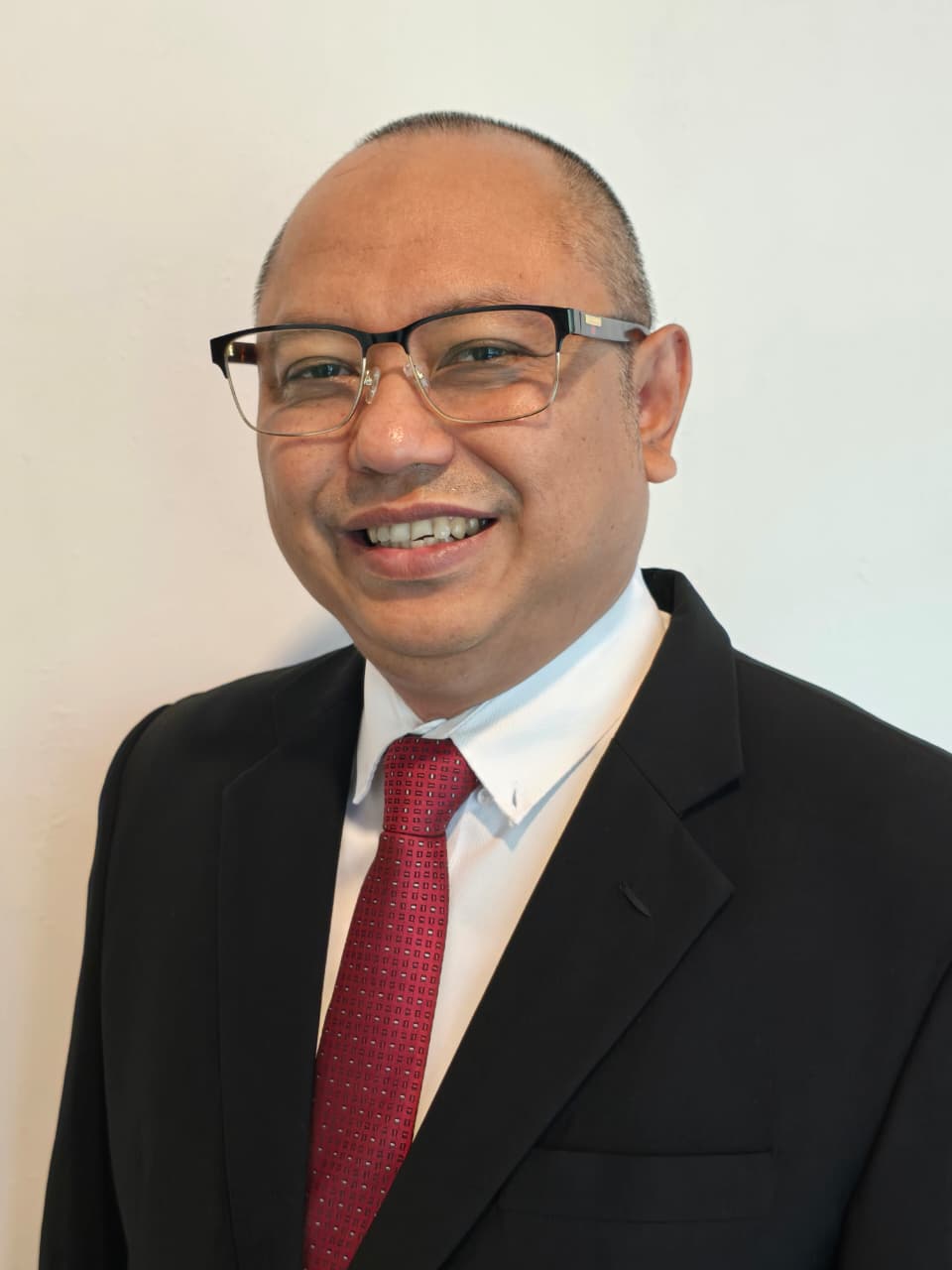 Gatot Prio Utomo, founder of Utomo Institute, in a dark suit and red tie.